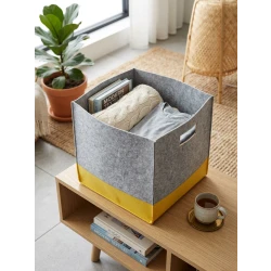 A modern, two-tone gray and yellow fabric storage box made of high-quality felt fabric with side handles for easy carrying. Ideal for organizing toys, clothes, and books, and adding a stylish decorative touch to your home